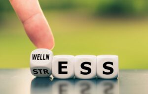 hand changing the word stress to wellness